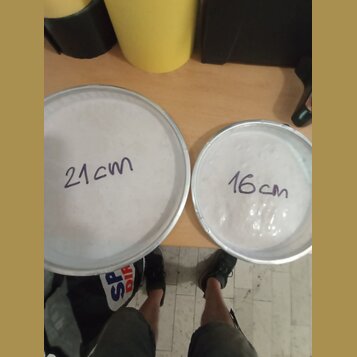 Dvě bílé bubnové membrány v kovových obručích. Na levé, větší membráně je ručně napsáno „21cm“ a na pravé, menší membráně „16cm“. Povrchy jsou bílé a…