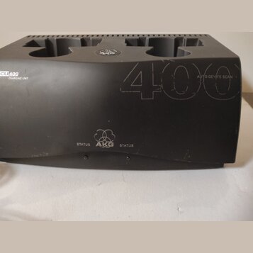 Černá nabíjecí stanice s nápisy CU400 CHARGING UNIT a AUTO DEVICE SCAN. Na přední straně je umístěno logo AKG doprovázené slovem STATUS z obou stran.…