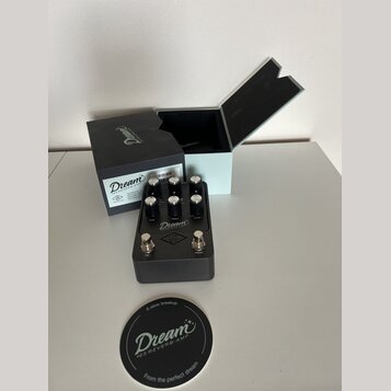 Šedý efekt pedál s nápisem Dream '65 REVERB-AMP. Na horní části jsou čtyři černé ovládací knoflíky s popisky DRIVE, TONE, VOLUME a REVERB, v dolní čá…