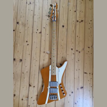 Elektrická basová kytara s hnědým trupem a hnedým krkem. Na hlavě je nápis "Squier". Trup má bílé dekorativní pruhy a dva snímače s kovovými kryty. P…