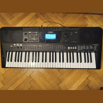 Černý digitální klavír s bílými a černými klávesami. Na horní části je logo YAMAHA, displej s nápisem BrandPro a vpravo označení modelu PSR-E463. Nás…