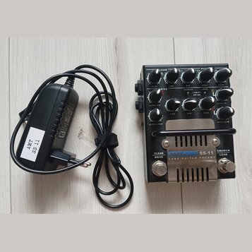 Černý kytarový předzesilovač s kovovým šasi a stříbrným spodním panelem. Na přístroji jsou nápisy AMT SS-11 TUBE GUITAR PREAMP, CLEAN DRIVE, CRUNCH L…