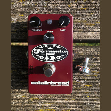 Bordeaux červený efekt pedál s nápisy Formula № 5, catalinbread a MECHANISMS OF MUSIC. Na horní straně jsou tři černé oválné knoflíky s popisky VOLUM…
