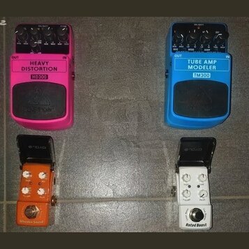 Čtyři efektové pedály v různých barvách. Růžový pedal má nápisy HEAVY DISTORTION, HD300 a logo behringer. Modrý pedal nese označení TUBE AMP MODELER,…
