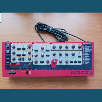Červený virtuální analogový syntetizátor s nápisem nord rack 2 virtual analog. Na předním panelu jsou umístěny početné ovládací knofíky, tlačítka a n…