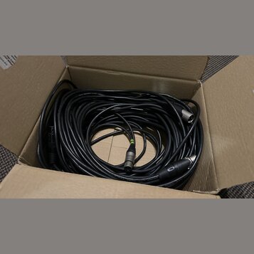 V kartonové krabici je smotaný černý kabel s konektory XLR. Na povrchu kabelu je nápis LOW NOISE CABLE a na jednom z konektorů je viditelné logo NEUT…