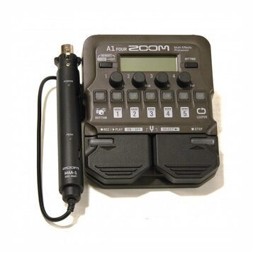 Šedý multifunkční procesor s nápisem A1 FOUR ZOOM Multi-Effects Processor. Zařízení obsahuje displej, ovládací knoflíky a pět stoupacích spínačů s čí…
