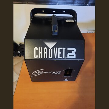 Černý generátor mlhy v kovovém hranatém provedení s úchytem. Na přední straně je bílý nápis CHAUVET DJ a níže označení HURRICANE HAZE 3D. Povrch přís…
