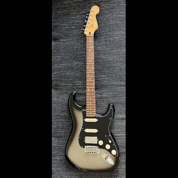 Elektrická kytara s černým bodies, hnědým hmatníkem a světle hnědou hlavou. Na hlavě je nápis Fender Stratocaster. Kytara má tři bílé snímače, tři bí…