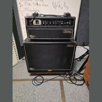 Černý kytarový kombozesilovač složený z komba a hlavního zesilovače. Na obou částech jsou vidět loga Kustom a nápisy Deep End. Přední panel zesilovač…
