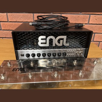Černý kytarový zesilovač s kovovou mřížkou, na které je nápis ENGL. Přední panel obsahuje ovládací knoflíky a nápisy Input, Clean Gain, Lead Gain, Ba…