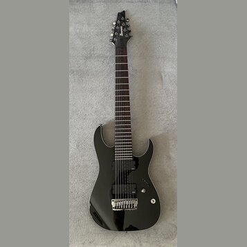 Černá elektrická kytara s černým hardwarem a tmavým hmatníkem. Na hlavě je svisle napsaný bílý nápis Ibanez. Kytara má dva humbuckery, jeden ovládací…
