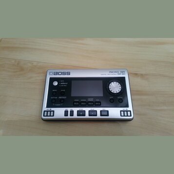 Stříbrný digitální rekordér s nápisy BOSS a MICRO BR DIGITAL RECORDER BR-80. Zařízení má černé ovládací prvky, displej a tlačítka s označením MENU, A…