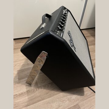 Černý kytarový kombo zesilovač s bílou textilní maskou a kovovými prvky. Na horním ovládacím panelu je nápis STRATOCASTER a logo Fender. Zesilovač má…