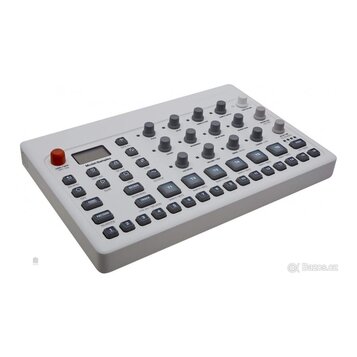 Světle šedý sampler s digitálním displejem a řadou ovládacích tlačítek a potenciometrů. Na panelu je nápis Model:Samples. Zařízení vykazuje čistý pov…
