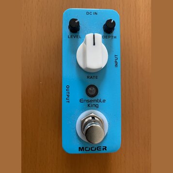 Modře barevný efekt pedál s bílým ovládacím knoflíkem a dvěma malými černými potenciometry. Na šasi jsou nápisy DC IN, LEVEL, DEPTH, INPUT, RATE a OU…