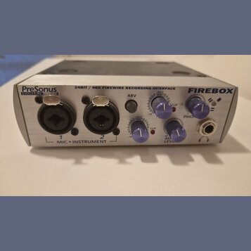 Stříbrný zvukový interface s nápisy PreSonus DIGITAL audio, 24BIT / 96K FIREWIRE RECORDING INTERFACE a FIREBOX. Přední panel obsahuje dva XLR vstupy…