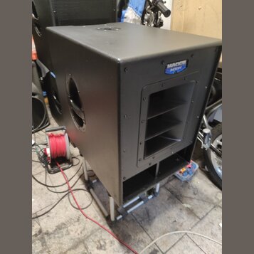 Černý aktivní subwoofer v hranatém korpusu s matným povrchem. Na horním pravém rohu je modro-bílé logo s nápisem MACKIE Active. Přední strana obsahuj…