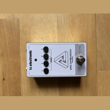 Bílý efekt pedál s nápisy tc electronic, 3RD DIMENSION a CHORUS. Na horní straně jsou čtyři černé přepínače označené čísly 1 až 4 a nápis MODE u červ…