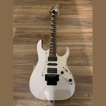 Bílá elektrická kytara s perleťovým pickguardem a hnědým hmatníkem. Na hlavě je viditelné logo Jackson. Nástroj má tři humbuckery, jeden ovládací kno…