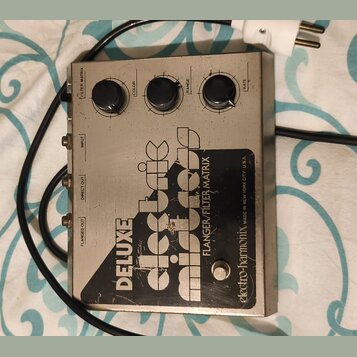 Stříbrný efekt pedál s nápisy DELUXE electric mistress a FLANGER/FILTER MATRIX. V dolní části je logo electro-harmonix a text MADE IN NEW YORK CITY U…