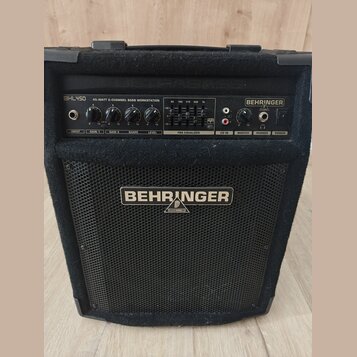 Černý basový kombo zesilovač značky BEHRINGER v textilním potahu. Na horním ovládacím panelu je nápis BXL450 45-WATT 2-CHANNEL BASS WORKSTATION a ovl…