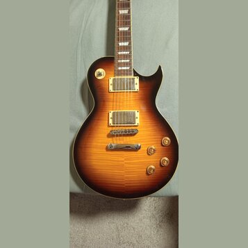 Elektrická kytara s tmelem v provedení sunburst a viditnou strukturou dřeva. Nástroj má dva humbuckery s krémovými rámečky, Tune-o-matic most a stopb…