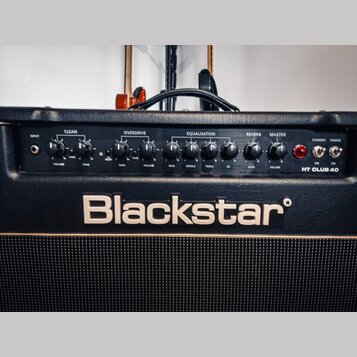 Detailní pohled na ovládací panel kytarového komba černé barvy. Na panelu jsou nápisy CLEAN, OVERDRIVE, EQUALISATION, REVERB a MASTER s řadou ovládac…