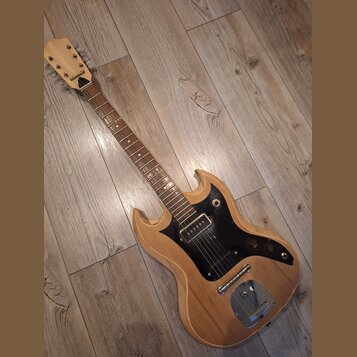 Elektrická kytara s přírodním dřevěným povrchem a černým pickguardem. Na hlavě hmatníku je vidět nápis "Epiphone". Nástroj vykazuje známky opotřebení…