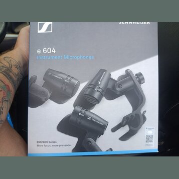 Fotografie znázorňuje krabici od mikrofonů s nápisy e 604 a Instrument Microphones. Na obalu jsou zobrazeny tři černé mikrofony s logem SENNHEISER a…