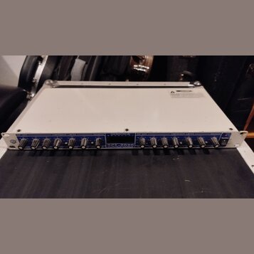 Bíle provedené rackové studio zařízení s modrým předním panelem. Na panelu jsou nápisy EXP / GATE, COMPRESSOR / LIMITER a ENHANCER, doprovázené řadou…