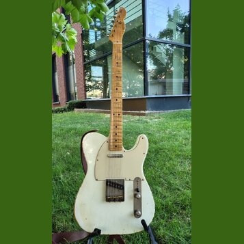 Elektrická kytara typu Telecaster v krémové barvě s javorovým hnedým hmatníkem. Tělo vykazuje známky opotřebení v podobě odřeni a škrábanců, zejména…