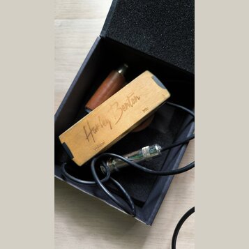 Dřevěný kytarový pedál s nápisy „Harley Benton“, „Volume“ a „Mic“. Pedál je umístěn v černé krabici s pěnovou výplní spolu s černým kabelem a kovovým…