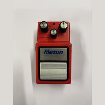 Červený efekt pedál s nápisem Maxon Compressor/Limiter. Horní část obsahuje tři černé ovládací knoflíky s kovovými vršekmi a popisky THRESHOLD, REDUC…