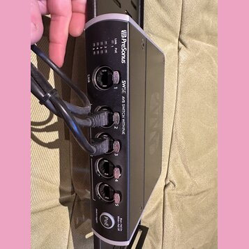 Černý síťový switch s bílými detaily a nápisy. Na zařízení je vidět logo Presonus a text SW5E AVB SWITCH WITH POE. Přístroj obsahuje pět RJ45 portů,…