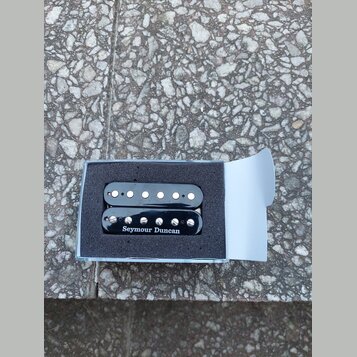Dvě černé elektrické snímače typu humbucker v originální modré krabičce s pěnovou výplní. Na spodním snímači je bílý nápis Seymour Duncan. Snímače ma…