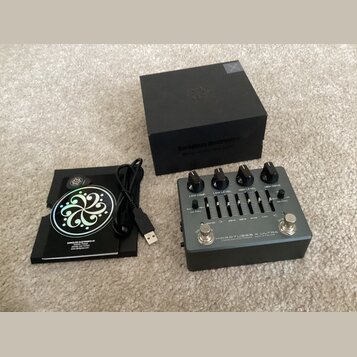 Na fotografii je kytarový efekt pedál stříbrné barvy s nápisem MICROTUBES X ULTRA a textem DARKGLASS ELECTRONICS MADE IN FINLAND. Zařízení má čtyři č…
