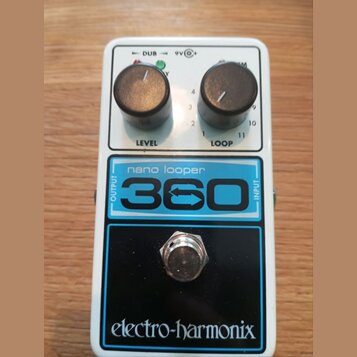 Bílý kytarový pedál s nápisy nano looper a 360 v modrém rámečku. V horní části jsou dva černé oválové knoflíky s popisky LEVEL a LOOP, nad nimi nápis…
