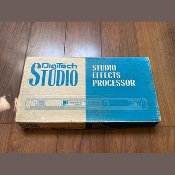 Kartonová krabice s modro-bílým potiskem. Na horní části je nápis Digitech STUDIO a STUDIO EFFECTS PROCESSOR. V prostřední části je znázorněn přístro…