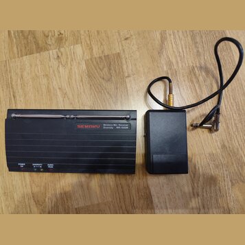 Černý bezdrátový přijímač s nápisy SEKAKU, Wireless Mic. Receiver Diversity WR-102DR a kontrolkami POWER ON, DIVERSITY A—B a AUDIO PEAK. Na horní str…