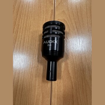Černý dynamický mikrofon s mřížkou v horní části. Na těle je bílý nápis AUDIX a pod ním model D6. Povrch mikrofonu je v dobrém stavu bez viditelného…