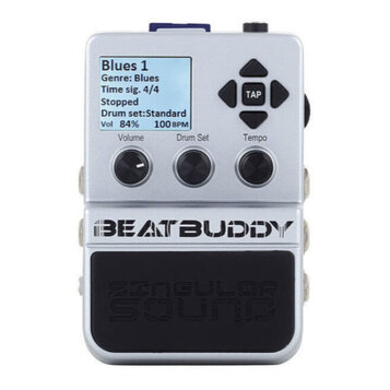 Stříbrný efekt pedál s displejem, na kterém je text: „Blues 1 Genre: Blues Time sig. 4/4 Stopped Drum set:Standard Vol 84% 100 BPM“. Nad ním jsou čty…