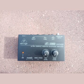 Černý kompaktní sluchátkový zesilovač s nápisy behringer a MicroMON MA400. Na předním panelu je text ULTRA-COMPACT MONITOR HEADPHONE AMPLIFIER, kontr…