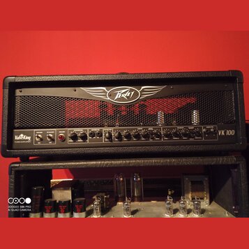 Černý kytarový kombozesilovač s kovovou mřížkou a logem Peavey v horní části. Na ovládacím panelu jsou nápisy ValveKing TUBE AMPLIFIER a VK 100. Pane…
