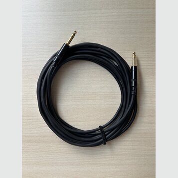 Černý audio kabel s pozlacenými 6,3mm jack konektory na obou koncích. Kabel je svinutý do kruhu a upevněný černým suchým zipem. Povrch kabelu i konek…