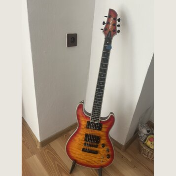 Elektrická kytara s trupem v červeno-žlutém sunburst provedení a viditnou strukturou dřeva. Na hlavě hmatníku je bílý nápis FERNANDES. Nástroj má dva…