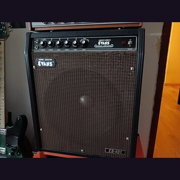 Černý kytarový kombo zesilovač s hnědou textilní maskou. Na ovládacím panelu jsou nápisy CREATIVE SOUND ® EVANS MUSICAL AMPLIFIER a popisky ovladačů…