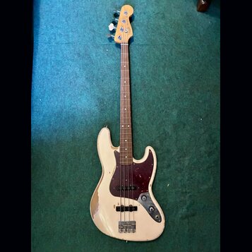 Bílá elektrická basová kytara s tmavě červeným pickguardem a hnedým hmatníkem. Na hlavě je vidět modré logo Fender a nápis Precision Bass. Povrch těl…