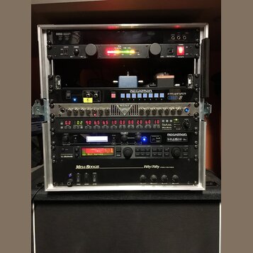 Stříbrný rackový kufřík s několika zařízeními. Obsahuje jednotky s nápisy KORG, The Rocket VM-100, ROCKTRON TriAxis, ROCKTRON HUSH a Mesa/Boogie Fift…