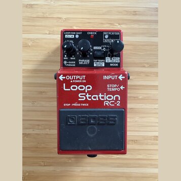 Červený efekt pedál Boss Loop Station RC-2. Na horní části jsou dva černé ovládací knoflíky, přepínač GUIDE a několik kontrolek s nápisy LOOP/ONE SHO…